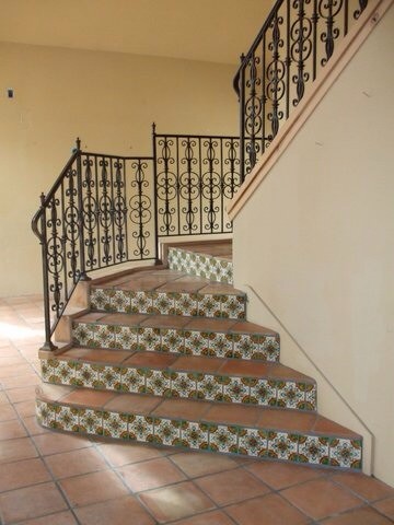 Пример оригинального дизайна: изогнутая лестница среднего размера в средиземноморском стиле с ступенями из терракотовой плитки, подступенками из плитки и металлическими перилами