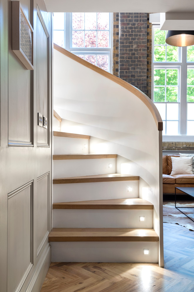 Contemporary wood curved wood railing staircase in London with painted wood risers.