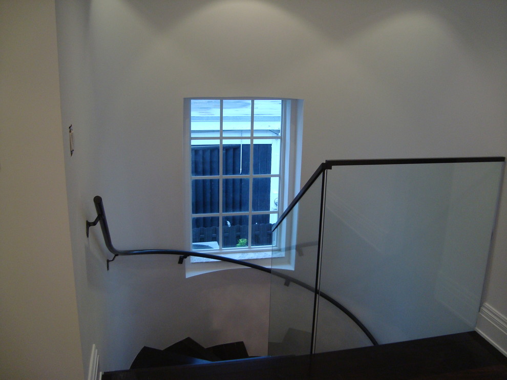 Ejemplo de escalera curva actual pequeña con escalones de madera, contrahuellas de madera y barandilla de vidrio