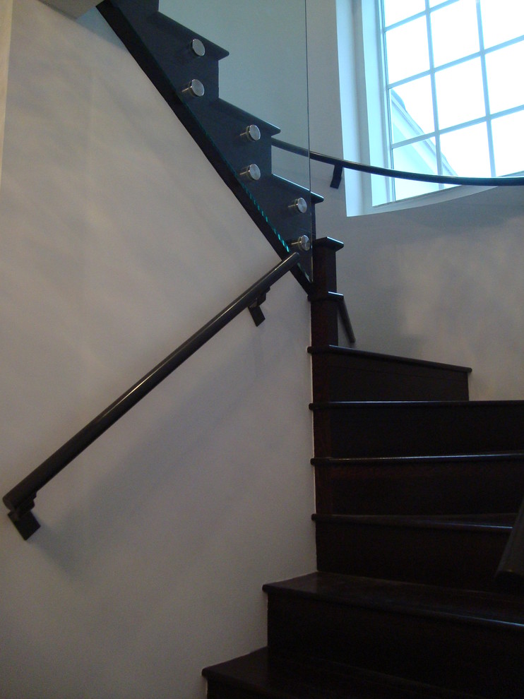 Réalisation d'un petit escalier courbe design avec des marches en bois, des contremarches en bois et un garde-corps en verre.