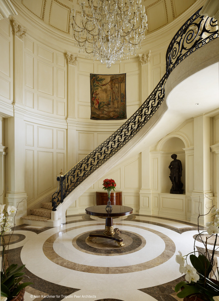 На фото: огромная изогнутая лестница в классическом стиле с мраморными ступенями, подступенками из мрамора и металлическими перилами