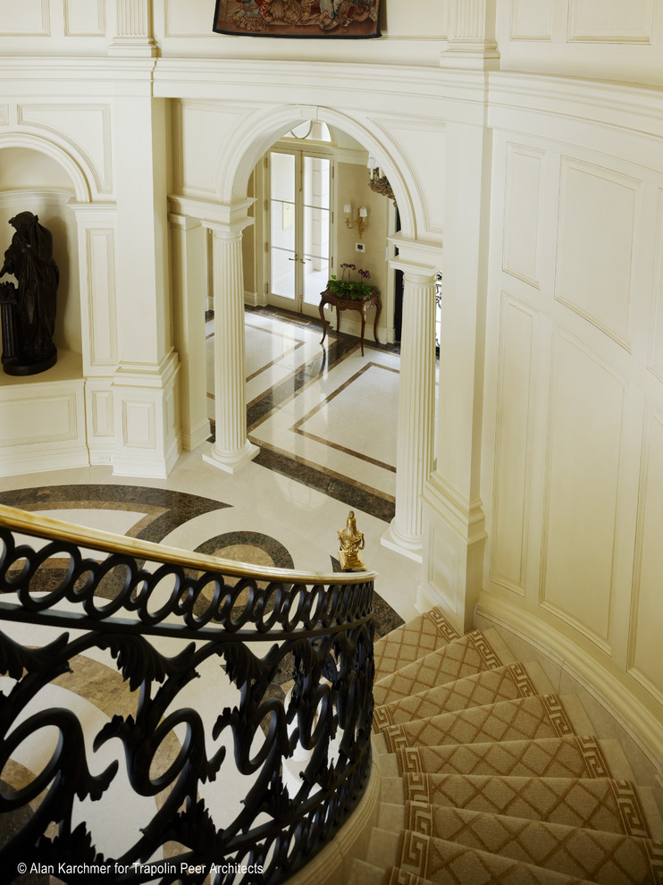 Cette photo montre un très grand escalier courbe chic en marbre avec des contremarches en marbre et un garde-corps en métal.