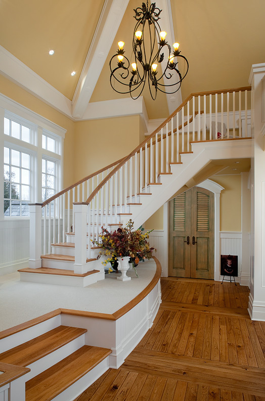 На фото: огромная изогнутая деревянная лестница в классическом стиле с деревянными ступенями