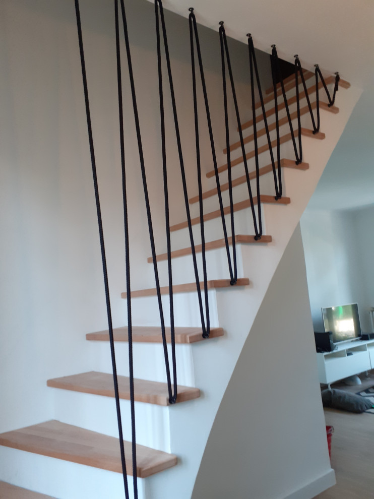 Diseño de escalera curva escandinava pequeña con escalones de madera, contrahuellas de hormigón y barandilla de varios materiales