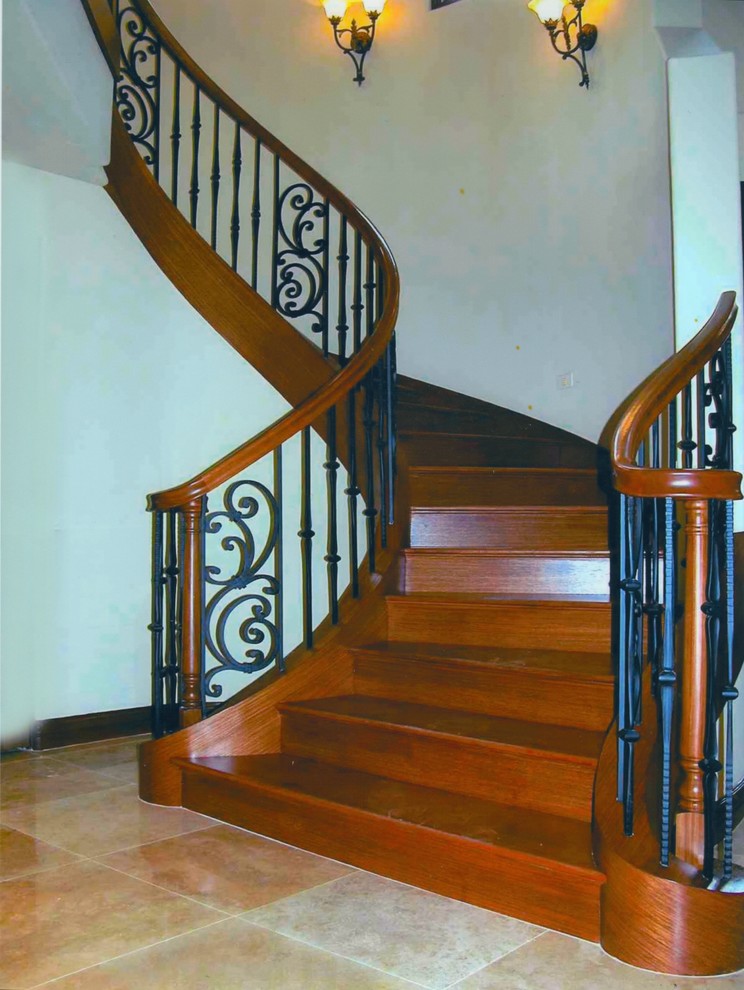 Cette image montre un escalier courbe méditerranéen de taille moyenne avec des marches en bois, des contremarches en bois et un garde-corps en métal.
