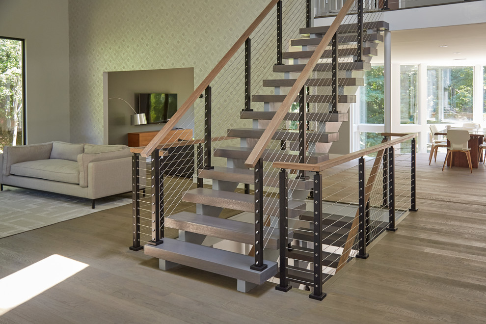 Photo of a large modern wood floating wood railing staircase in Other with feature lighting.