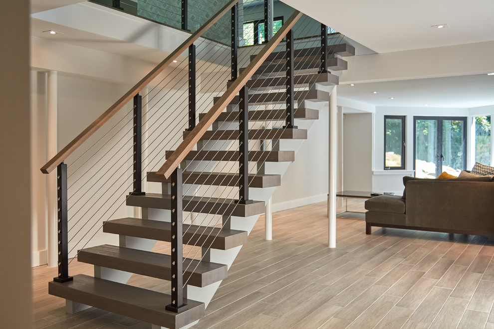 Ejemplo de escalera suspendida moderna grande con escalones de madera y barandilla de madera