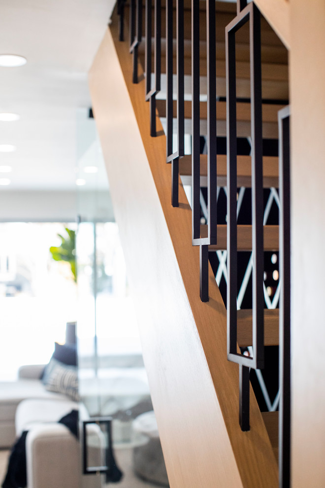 Foto de escalera en L minimalista de tamaño medio sin contrahuella con escalones de madera y barandilla de metal