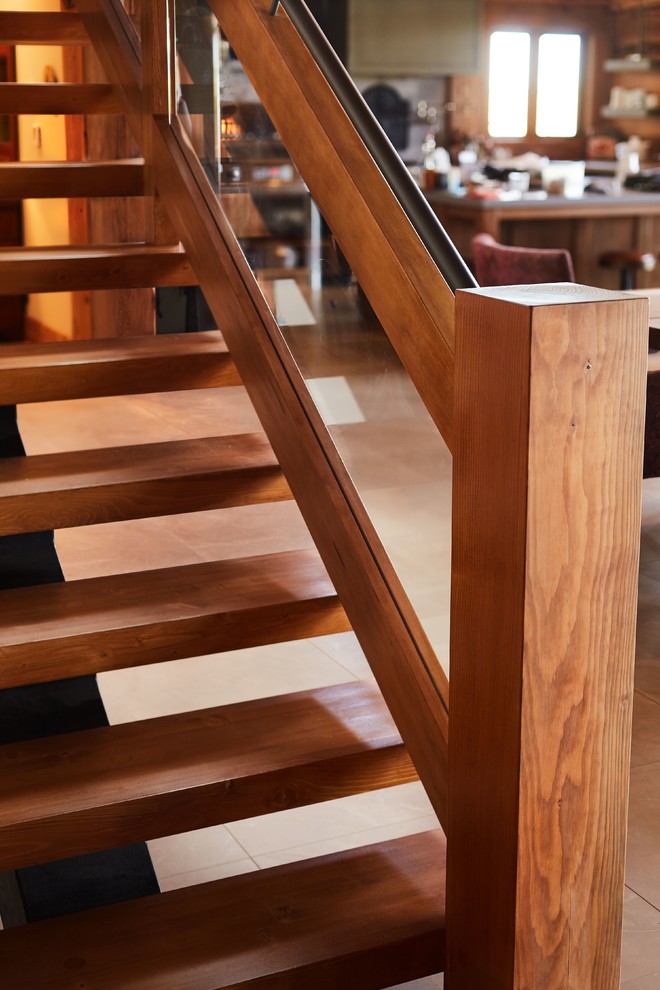 Diseño de escalera suspendida rural sin contrahuella con escalones de madera y barandilla de vidrio