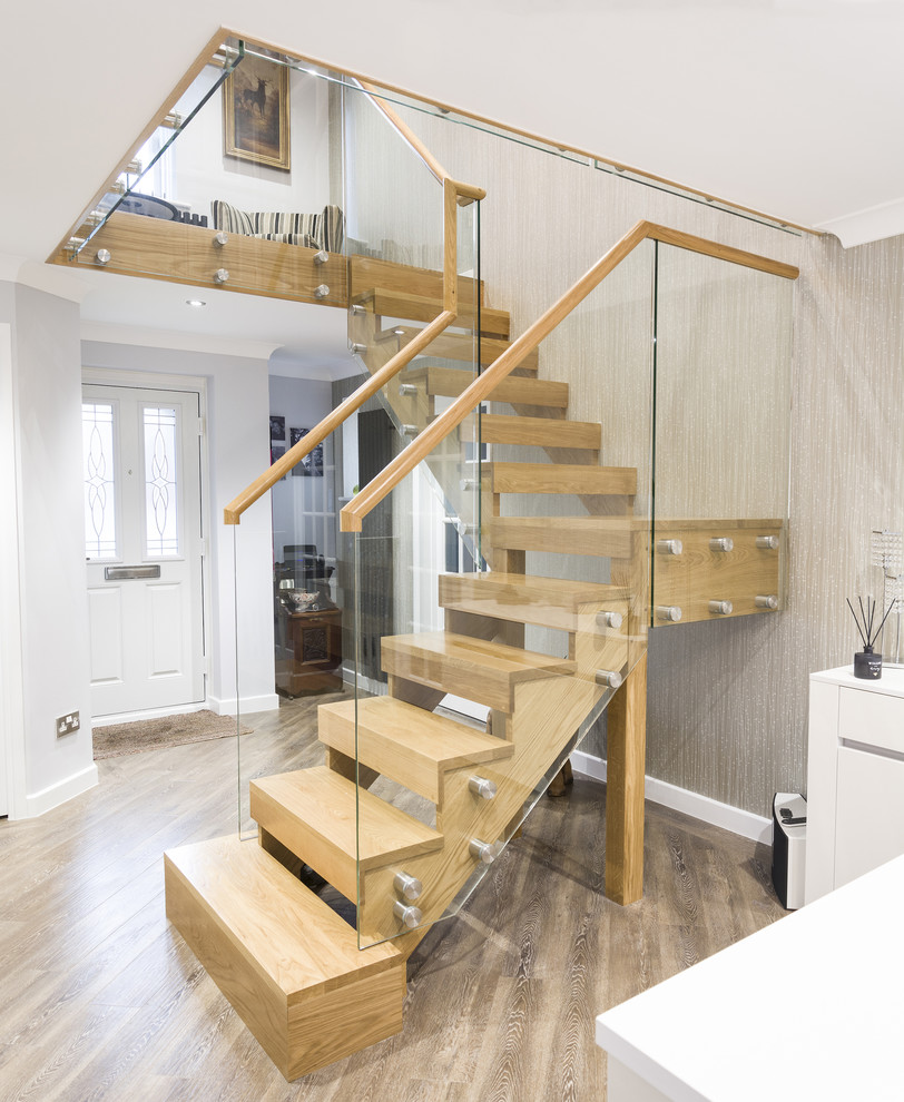Ejemplo de escalera en L actual de tamaño medio con escalones de madera, contrahuellas de madera y barandilla de vidrio