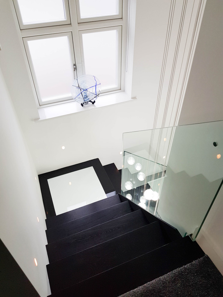 На фото: п-образная лестница среднего размера в современном стиле с деревянными ступенями и стеклянными перилами без подступенок с