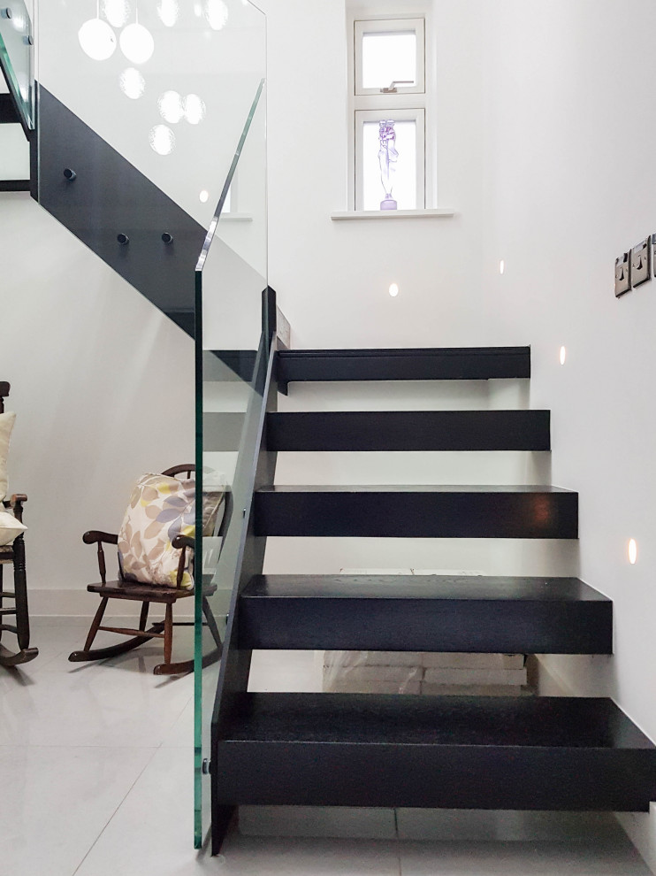 Пример оригинального дизайна: п-образная лестница среднего размера в современном стиле с деревянными ступенями и стеклянными перилами без подступенок