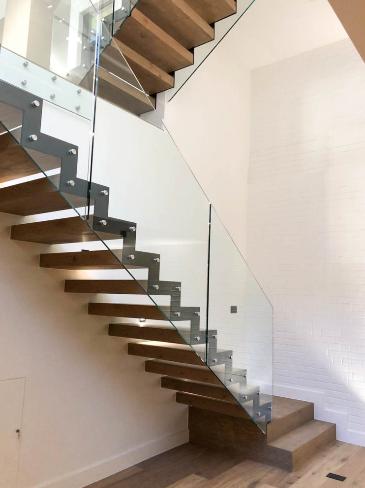 На фото: прямая лестница среднего размера в современном стиле с деревянными ступенями и стеклянными перилами без подступенок с