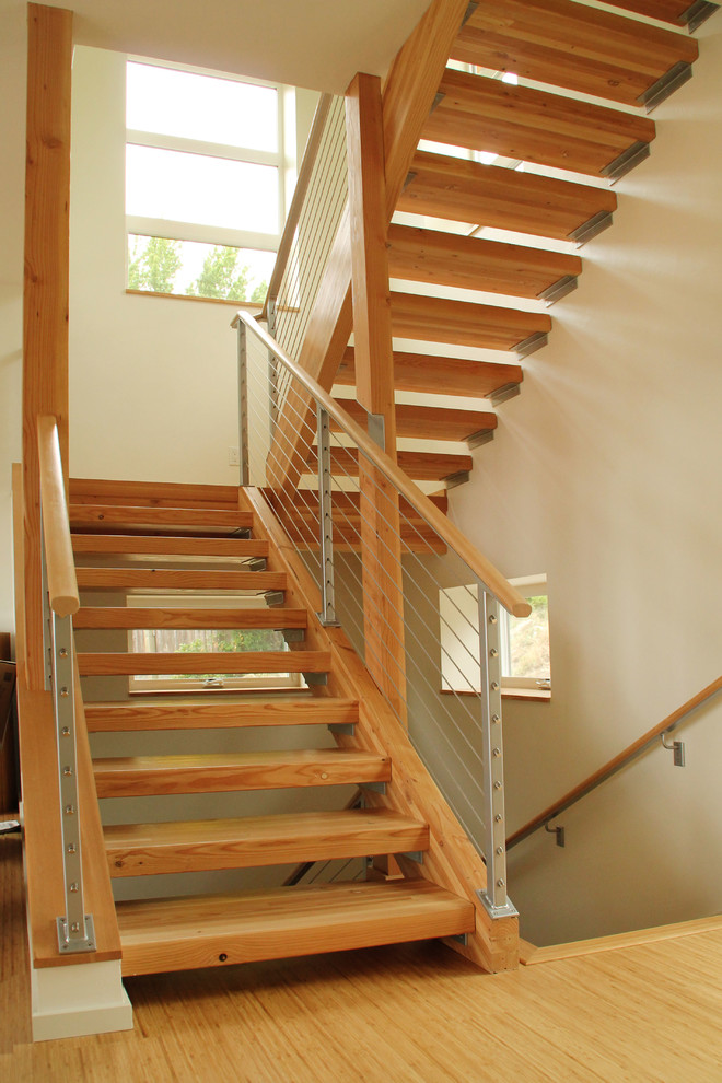 Diseño de escalera suspendida actual de tamaño medio con escalones de madera, contrahuellas de madera y barandilla de cable