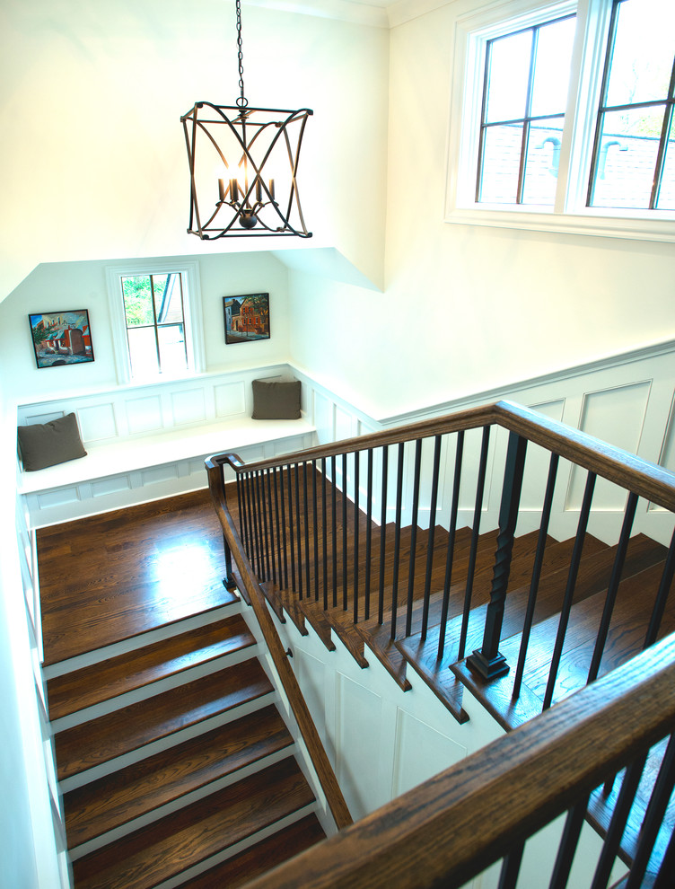 На фото: п-образная лестница в стиле неоклассика (современная классика) с деревянными ступенями и крашенными деревянными подступенками