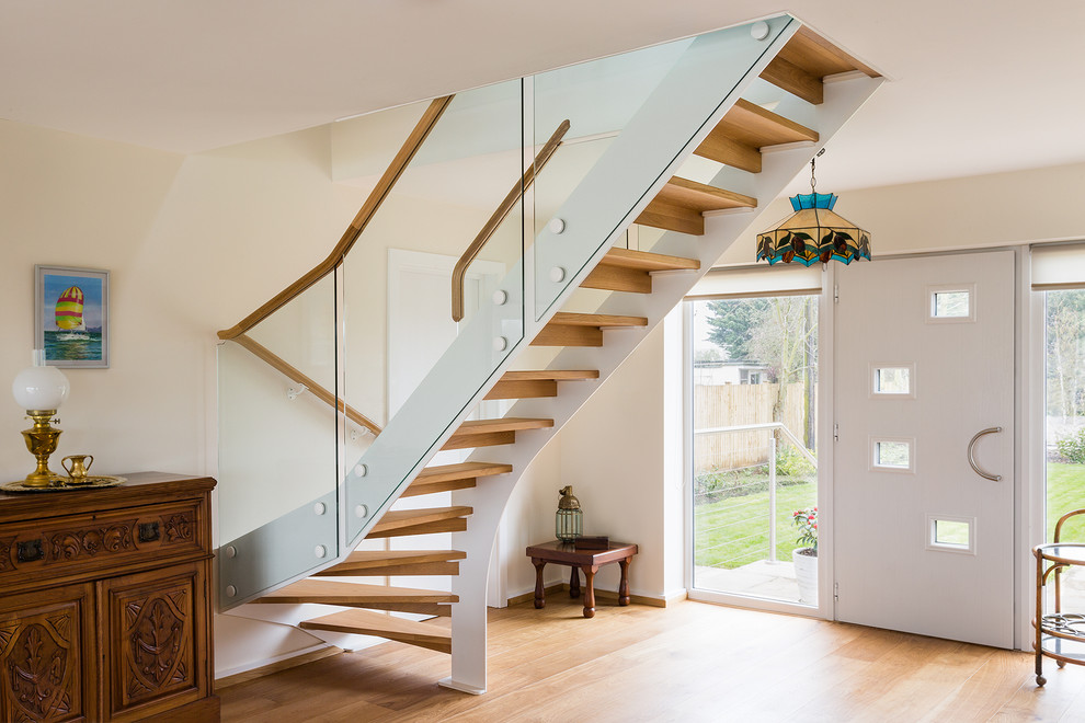Cette image montre un escalier sans contremarche bohème en L avec des marches en bois et un garde-corps en verre.