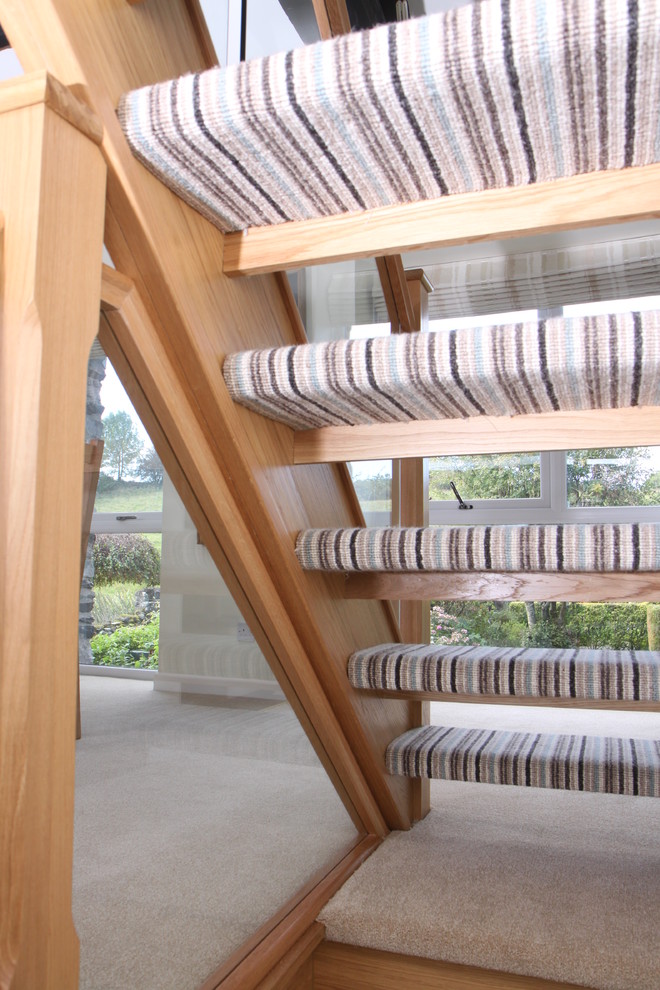 Diseño de escalera recta contemporánea con escalones enmoquetados, contrahuellas enmoquetadas y barandilla de vidrio