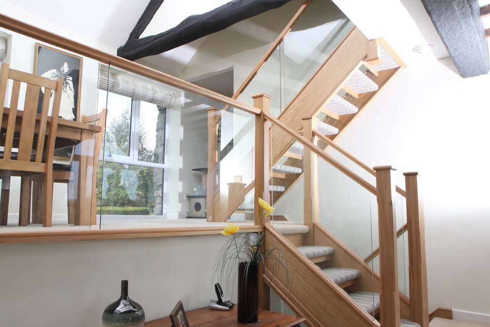 Стильный дизайн: прямая лестница в современном стиле с ступенями с ковровым покрытием, ковровыми подступенками и стеклянными перилами - последний тренд