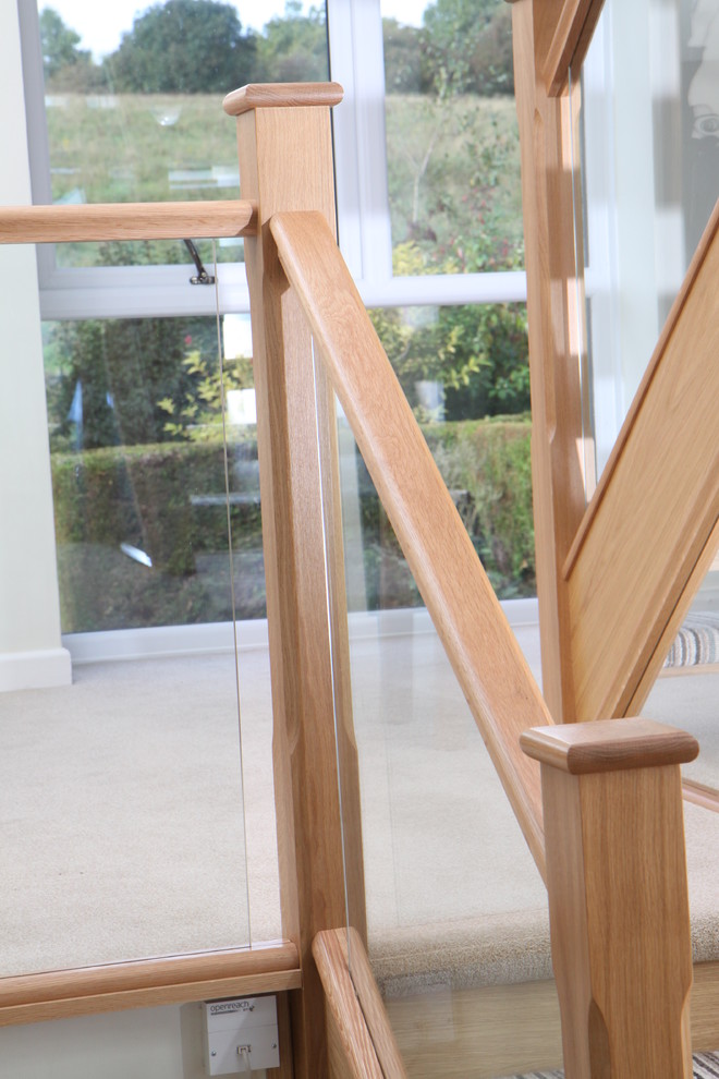 Ejemplo de escalera recta actual con escalones enmoquetados, contrahuellas enmoquetadas y barandilla de vidrio