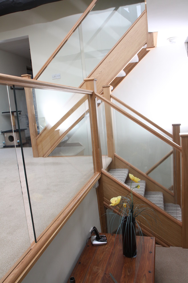 Modelo de escalera recta contemporánea con escalones enmoquetados, contrahuellas enmoquetadas y barandilla de vidrio