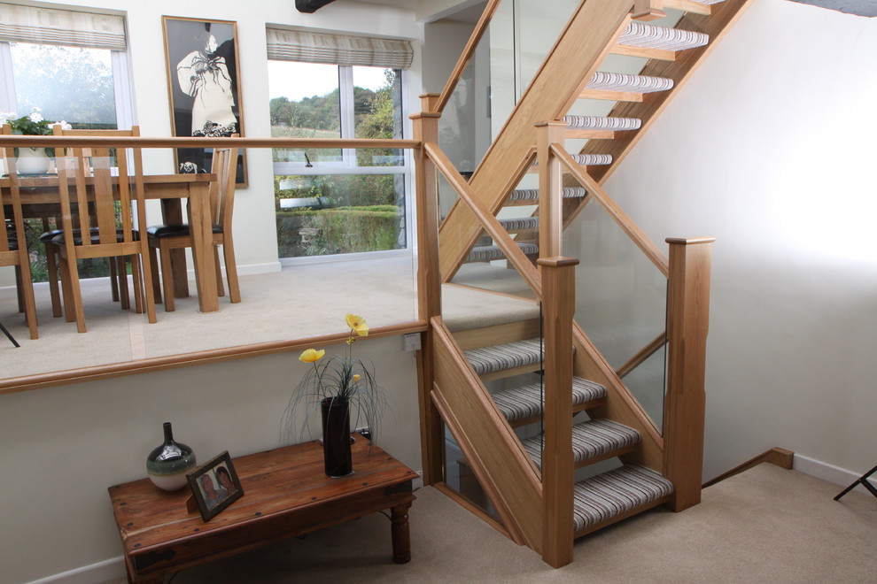 Diseño de escalera recta actual con escalones enmoquetados, contrahuellas enmoquetadas y barandilla de vidrio