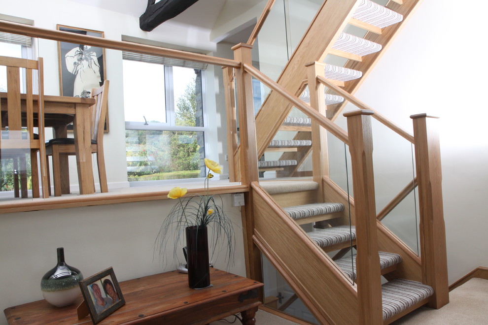 Imagen de escalera recta actual con escalones enmoquetados, contrahuellas enmoquetadas y barandilla de vidrio