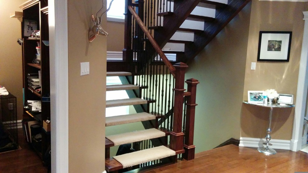 Diseño de escalera suspendida moderna grande sin contrahuella con barandilla de metal y escalones enmoquetados