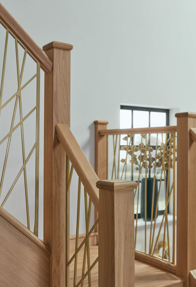 Cette image montre un grand escalier design en U avec des marches en bois, des contremarches en bois et un garde-corps en métal.
