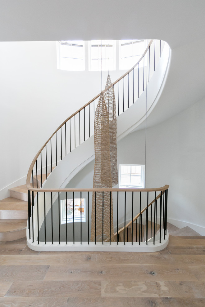 Cette photo montre un escalier courbe tendance de taille moyenne avec des marches en bois, des contremarches en bois et un garde-corps en métal.