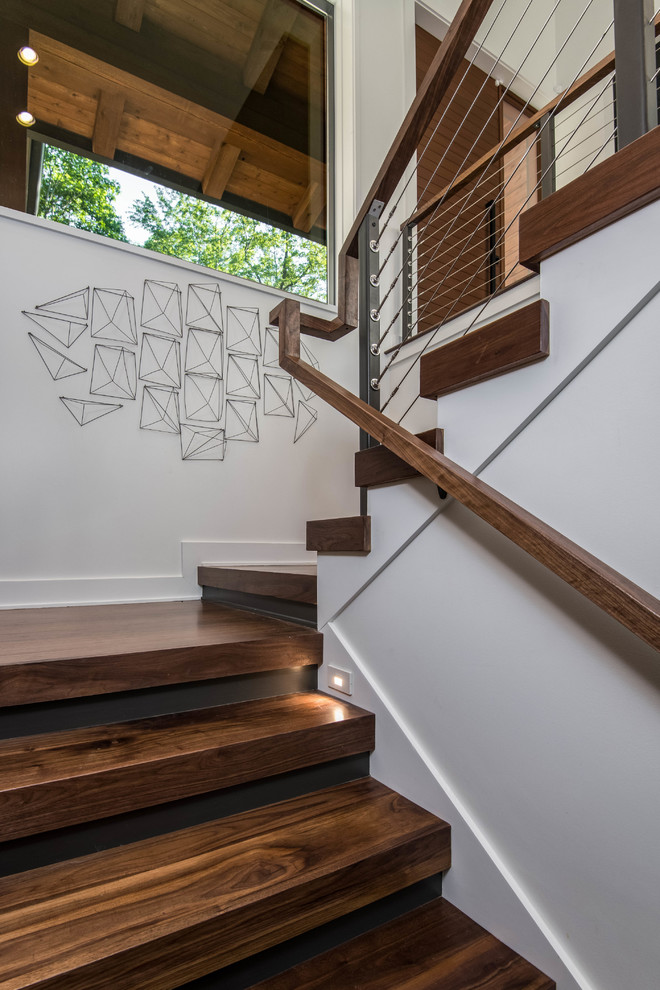 На фото: п-образная деревянная лестница среднего размера в стиле модернизм с деревянными ступенями и перилами из тросов