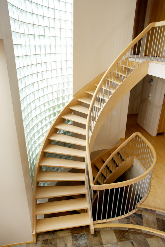 Imagen de escalera curva actual sin contrahuella con escalones de madera y barandilla de madera
