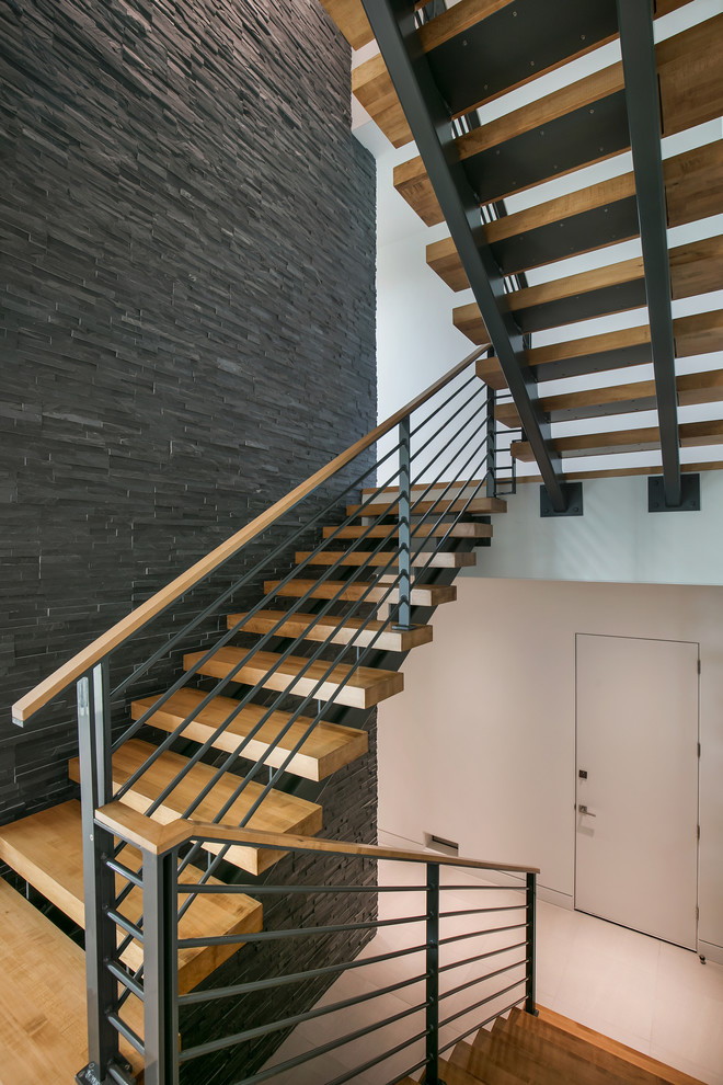 Cette image montre un grand escalier sans contremarche minimaliste en U avec des marches en bois et un garde-corps en matériaux mixtes.