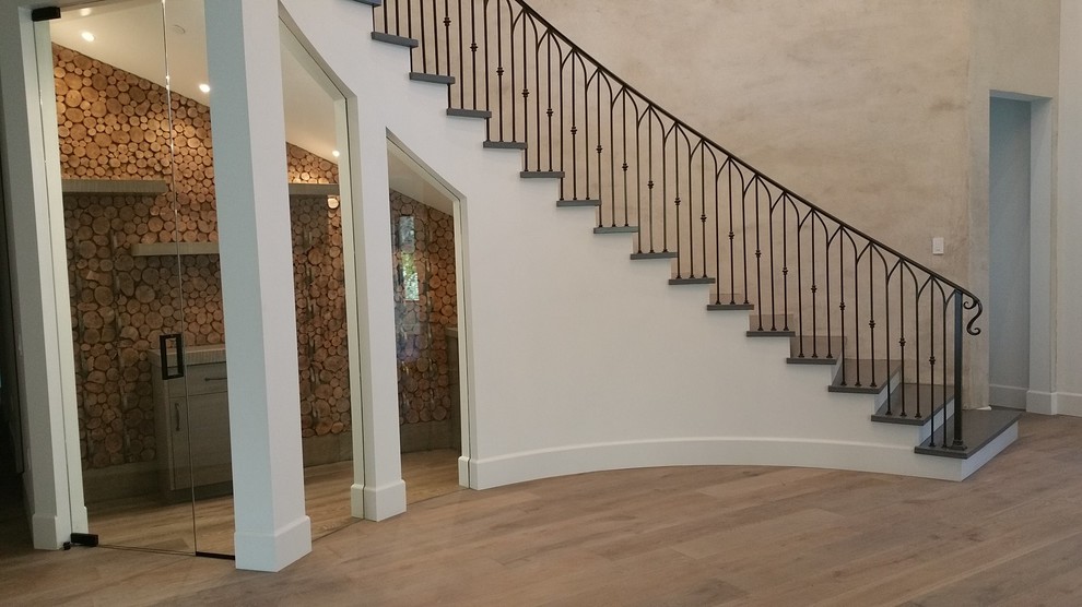 Diseño de escalera curva clásica grande con escalones de hormigón, contrahuellas de madera pintada y barandilla de metal