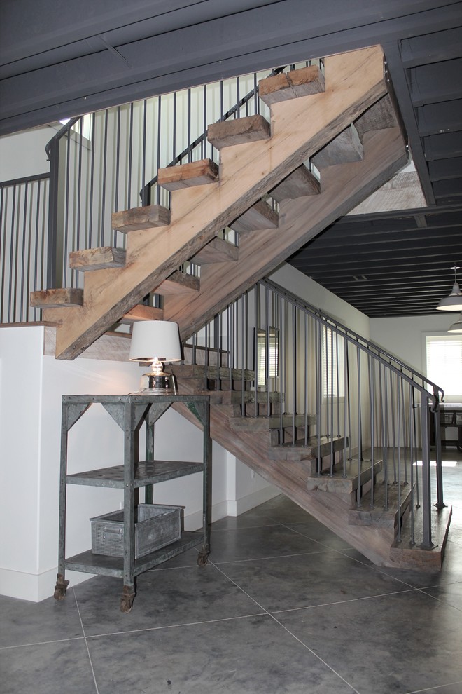 This is an example of a medium sized rustic wood u-shaped metal railing staircase in Other with open risers and feature lighting.