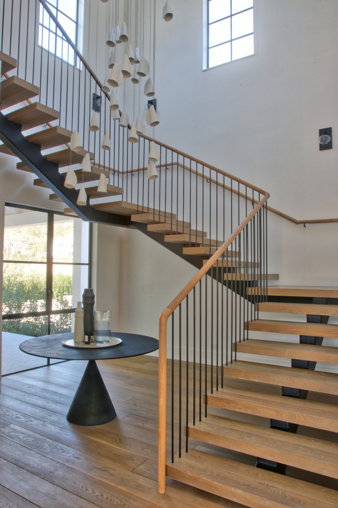 Imagen de escalera suspendida moderna grande sin contrahuella con escalones de madera y barandilla de varios materiales
