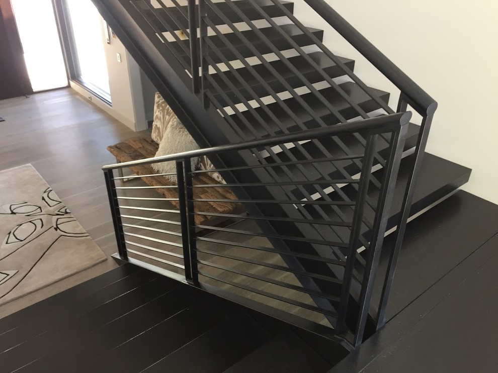 Inspiration for a medium sized modern wood u-shaped metal railing staircase in Other with open risers.