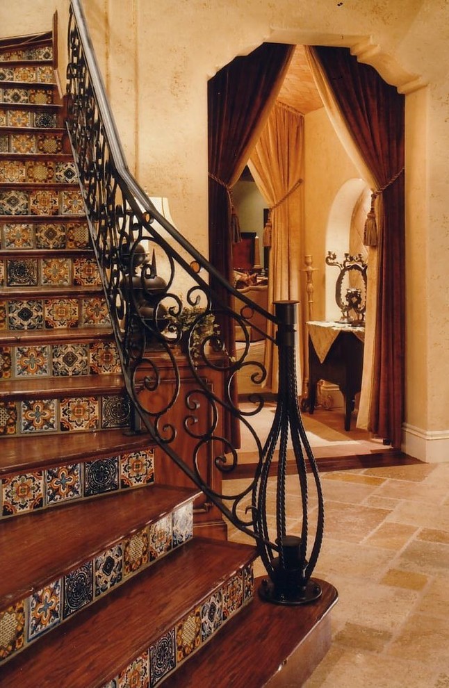 Staircase - mid-sized mediterranean wooden curved metal railing staircase idea in Orlando with tile risers