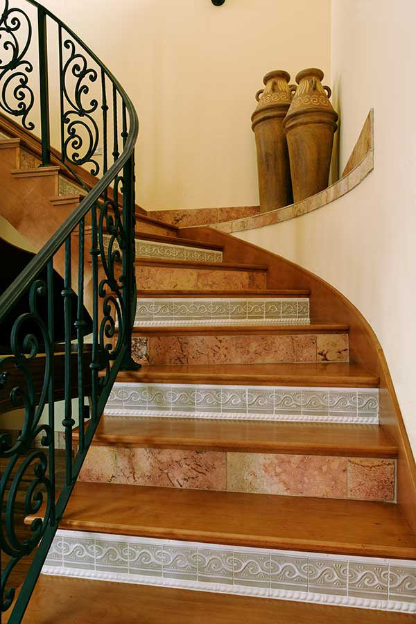 Источник вдохновения для домашнего уюта: изогнутая лестница среднего размера в средиземноморском стиле с деревянными ступенями, подступенками из плитки и металлическими перилами