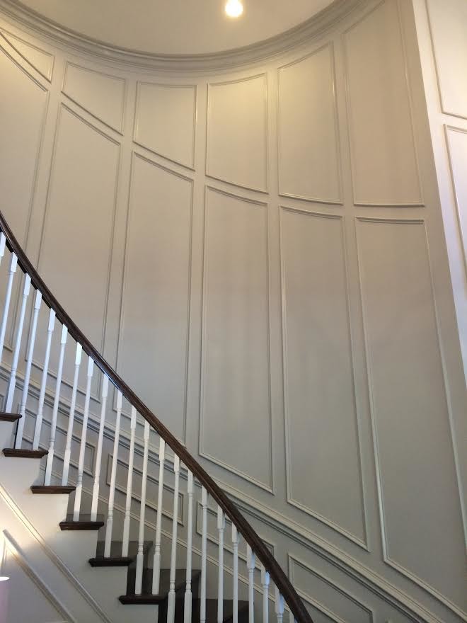 Diseño de escalera curva clásica grande con escalones de madera, contrahuellas de madera y barandilla de madera