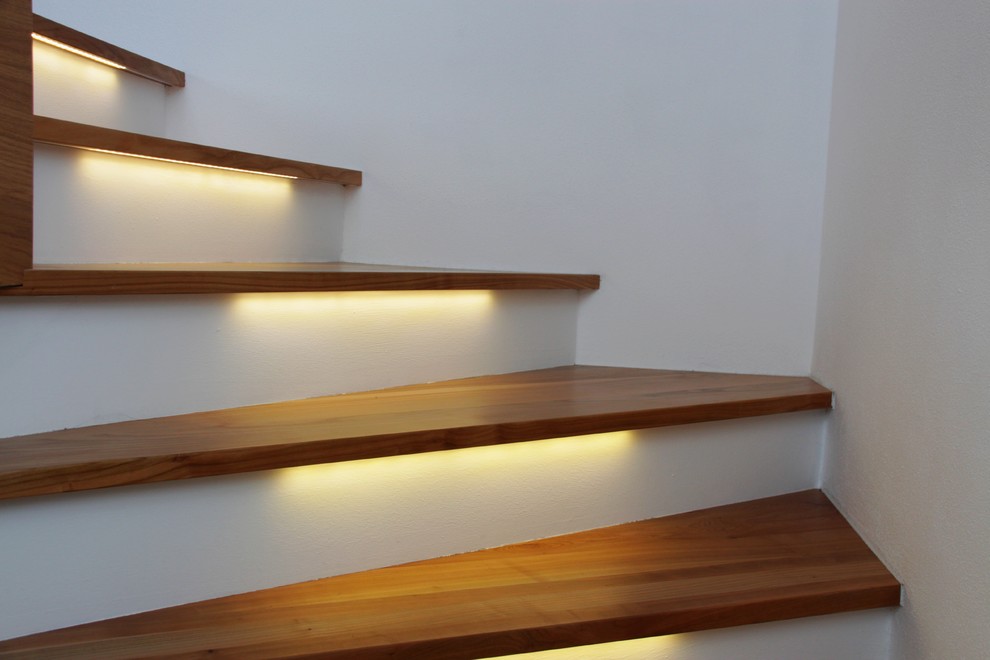 На фото: изогнутая лестница среднего размера в стиле модернизм с деревянными ступенями и крашенными деревянными подступенками