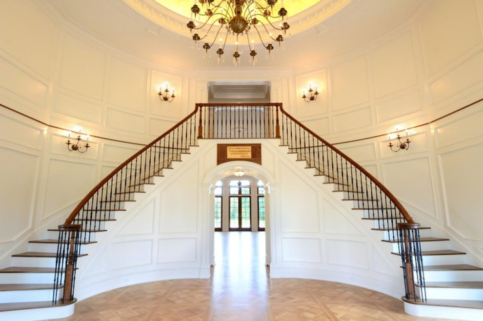 Cette image montre un très grand escalier peint courbe traditionnel avec des marches en bois et un garde-corps en matériaux mixtes.