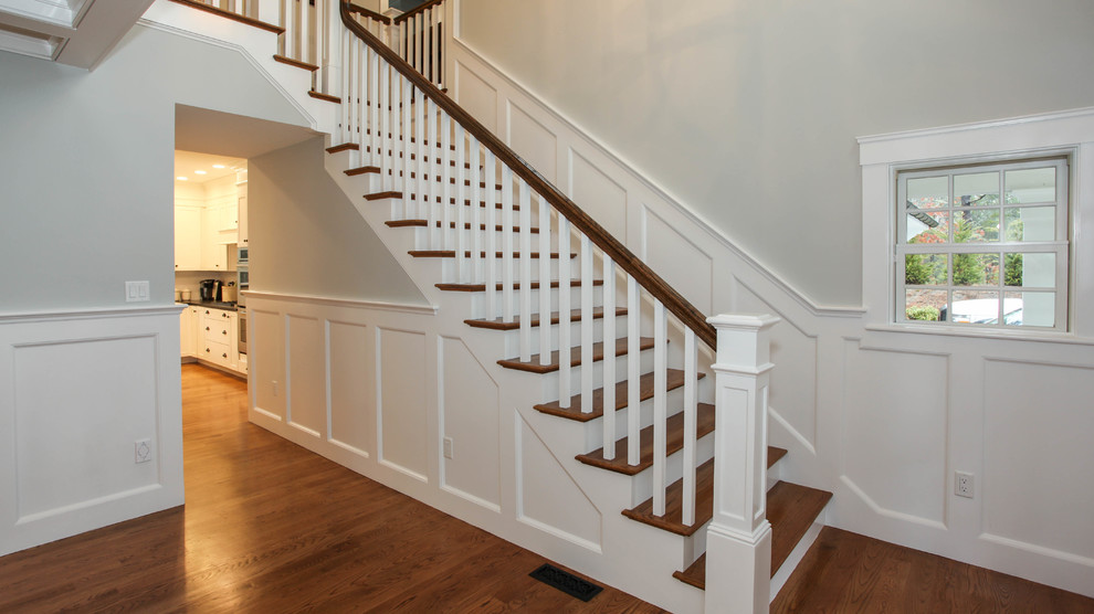 Imagen de escalera en L de estilo americano extra grande con escalones de madera y contrahuellas de madera pintada