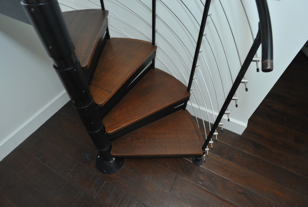 Aménagement d'un petit escalier hélicoïdal industriel avec des marches en bois et un garde-corps en métal.
