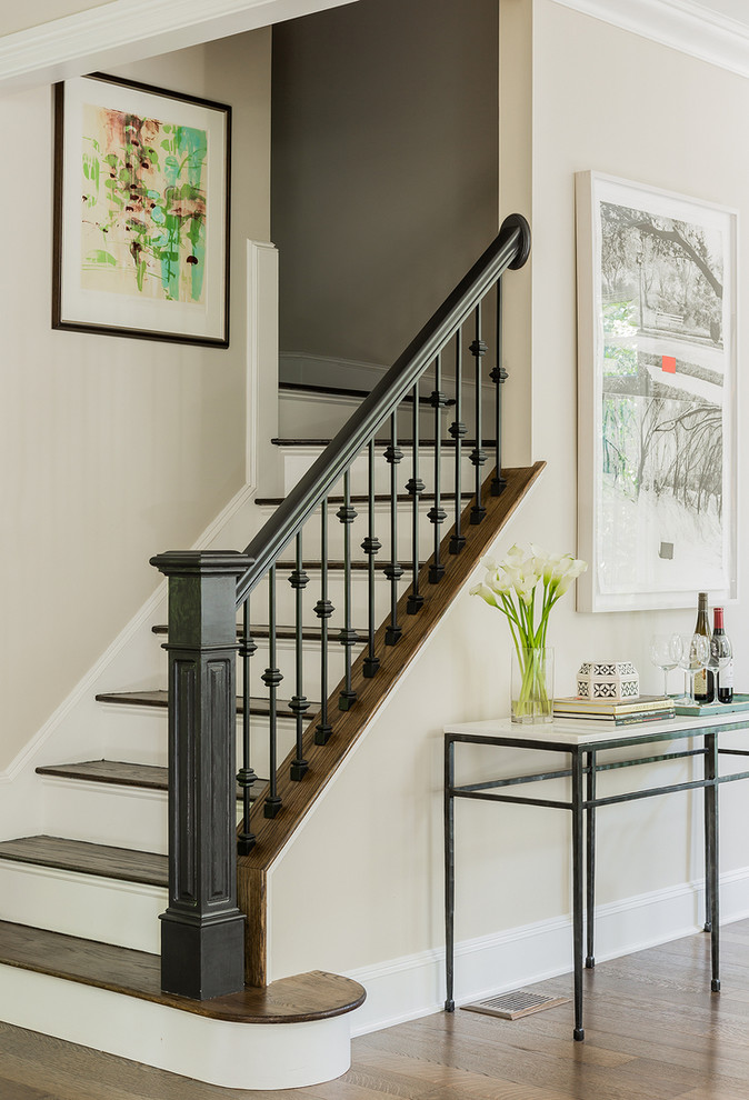 На фото: угловая лестница в классическом стиле с деревянными ступенями, крашенными деревянными подступенками и перилами из смешанных материалов