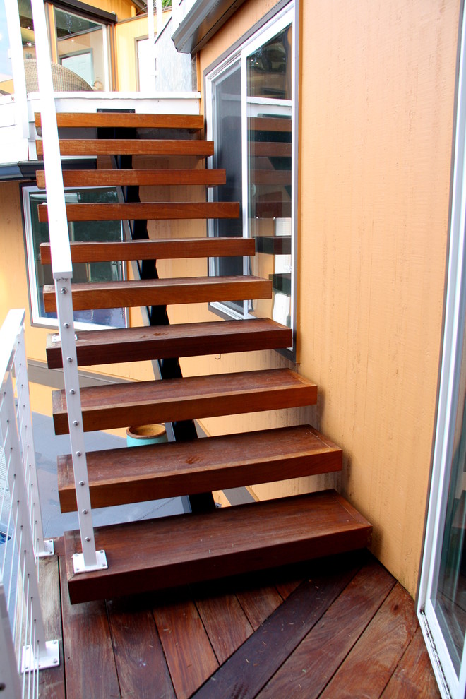 Bild på en liten funkis rak trappa i trä, med räcke i metall