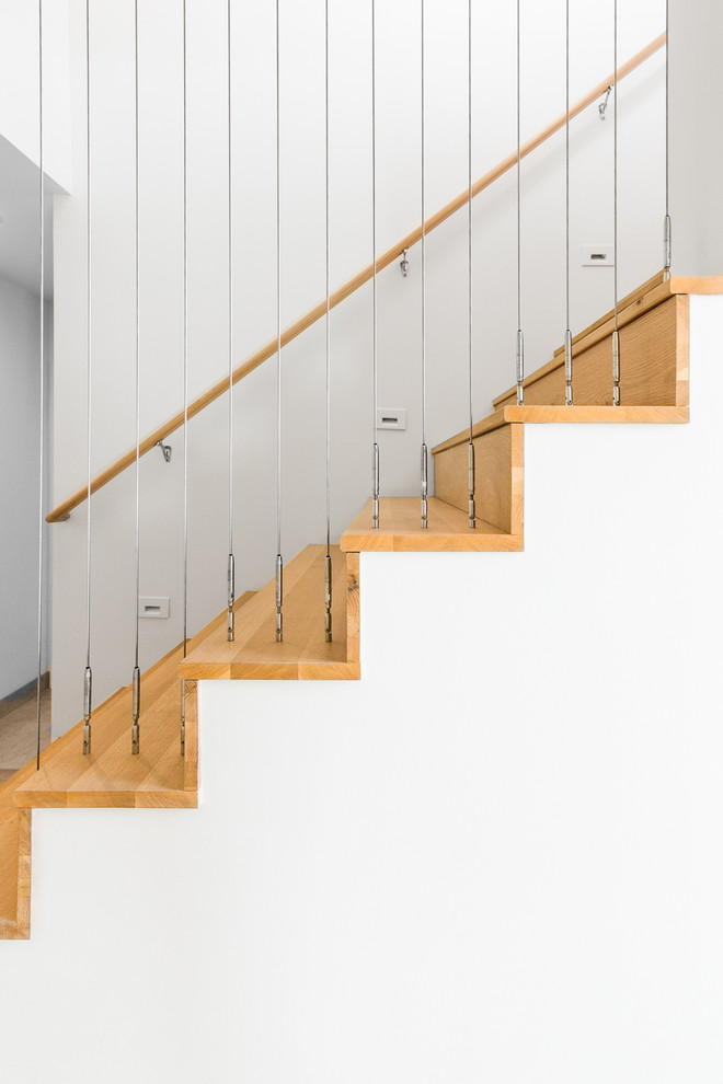 This is an example of a retro wood straight wire cable railing staircase in Portland with wood risers.