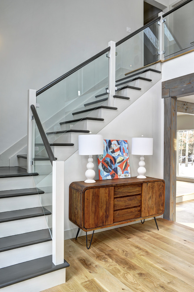 Réalisation d'un grand escalier peint design en L avec des marches en bois peint et éclairage.