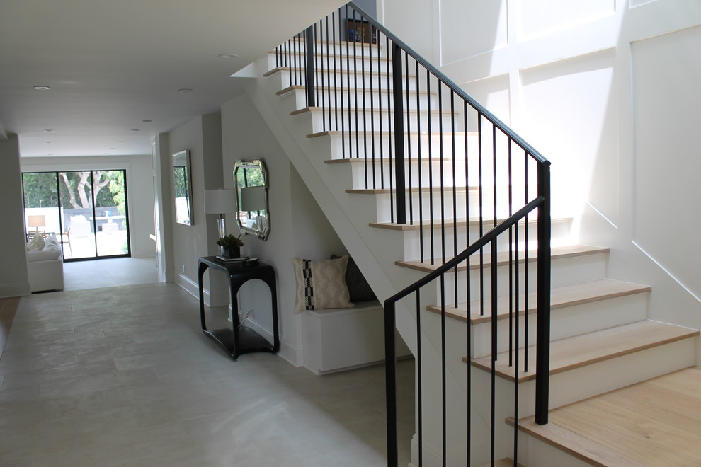 This is an example of a large classic wood l-shaped metal railing staircase in Los Angeles with painted wood risers.