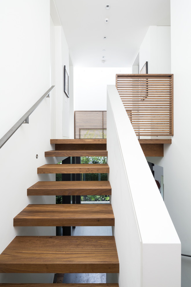 Idée de décoration pour un escalier sans contremarche design en L de taille moyenne avec un garde-corps en métal et des marches en bois.