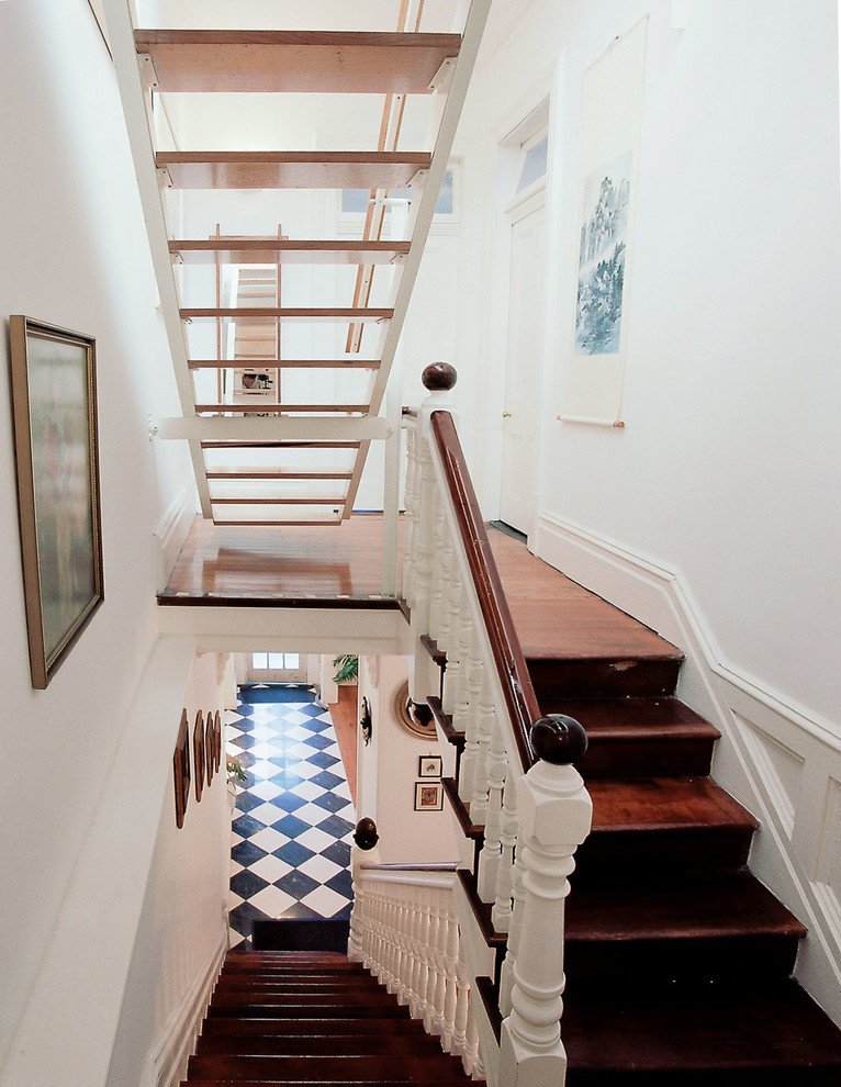 На фото: большая лестница на больцах в викторианском стиле с деревянными ступенями и деревянными перилами без подступенок